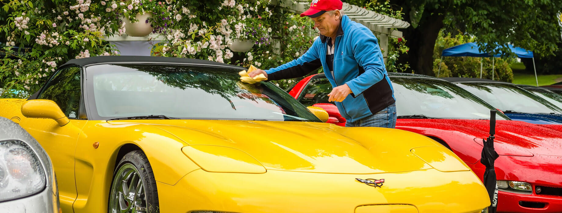 Man cleaning yellow sports car with a sponge.