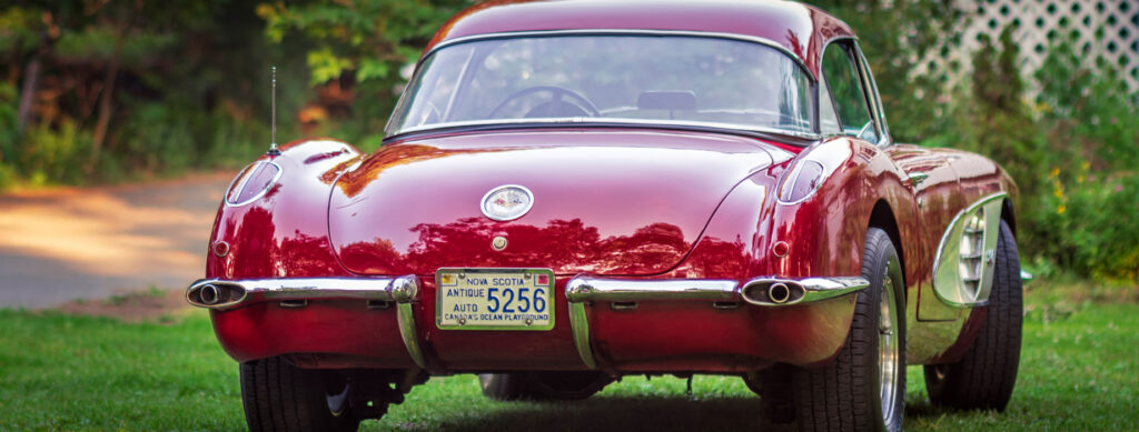 Classic red vintage car with a shiny exterior and old license plate.
