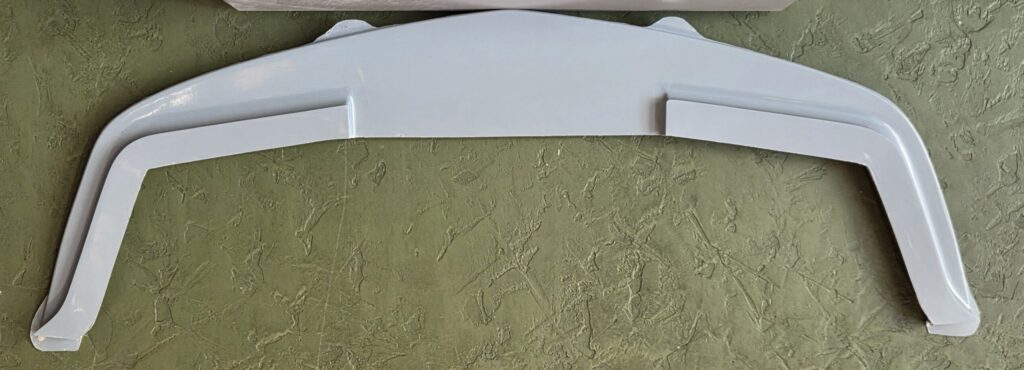white car spoiler resting against textured wall